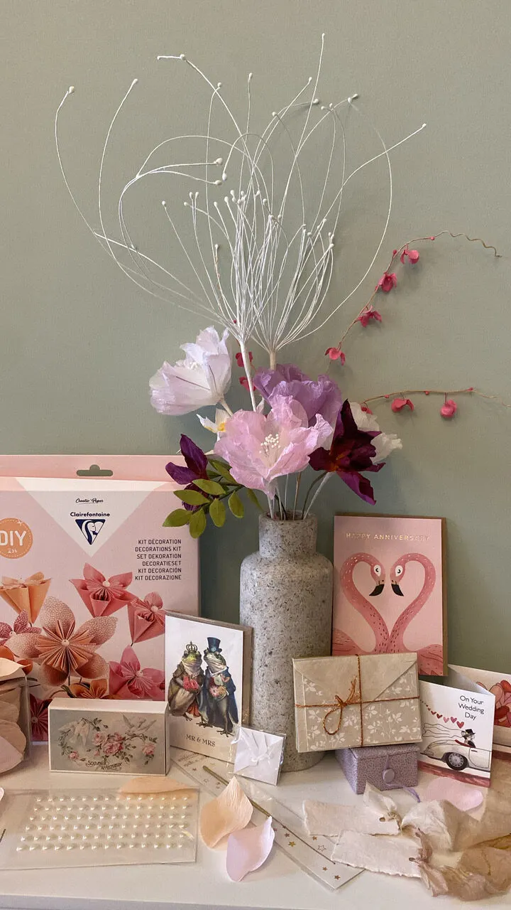 DIY-Set für Papierblümen neben einer Vase mit Papierblüten