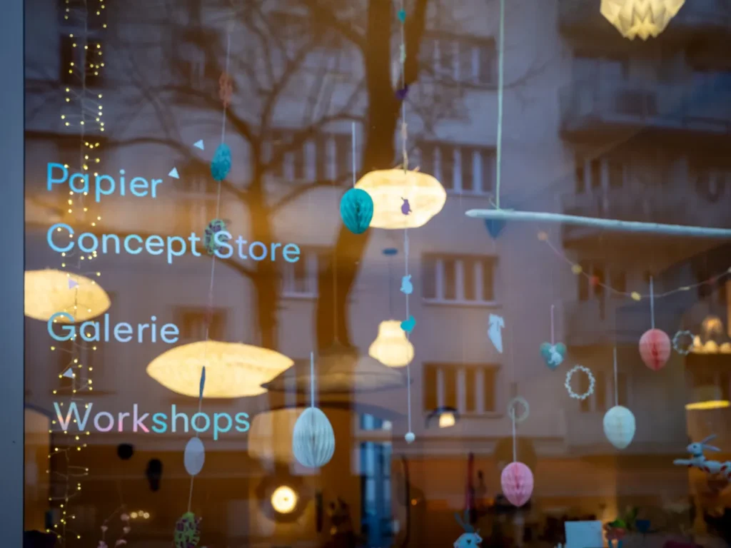 Beleuchtetes Schaufenster von L' Atelier Papier in der Grolmanstraße, Berlin-Charlottenburg, mit hängenden Papierobjekten