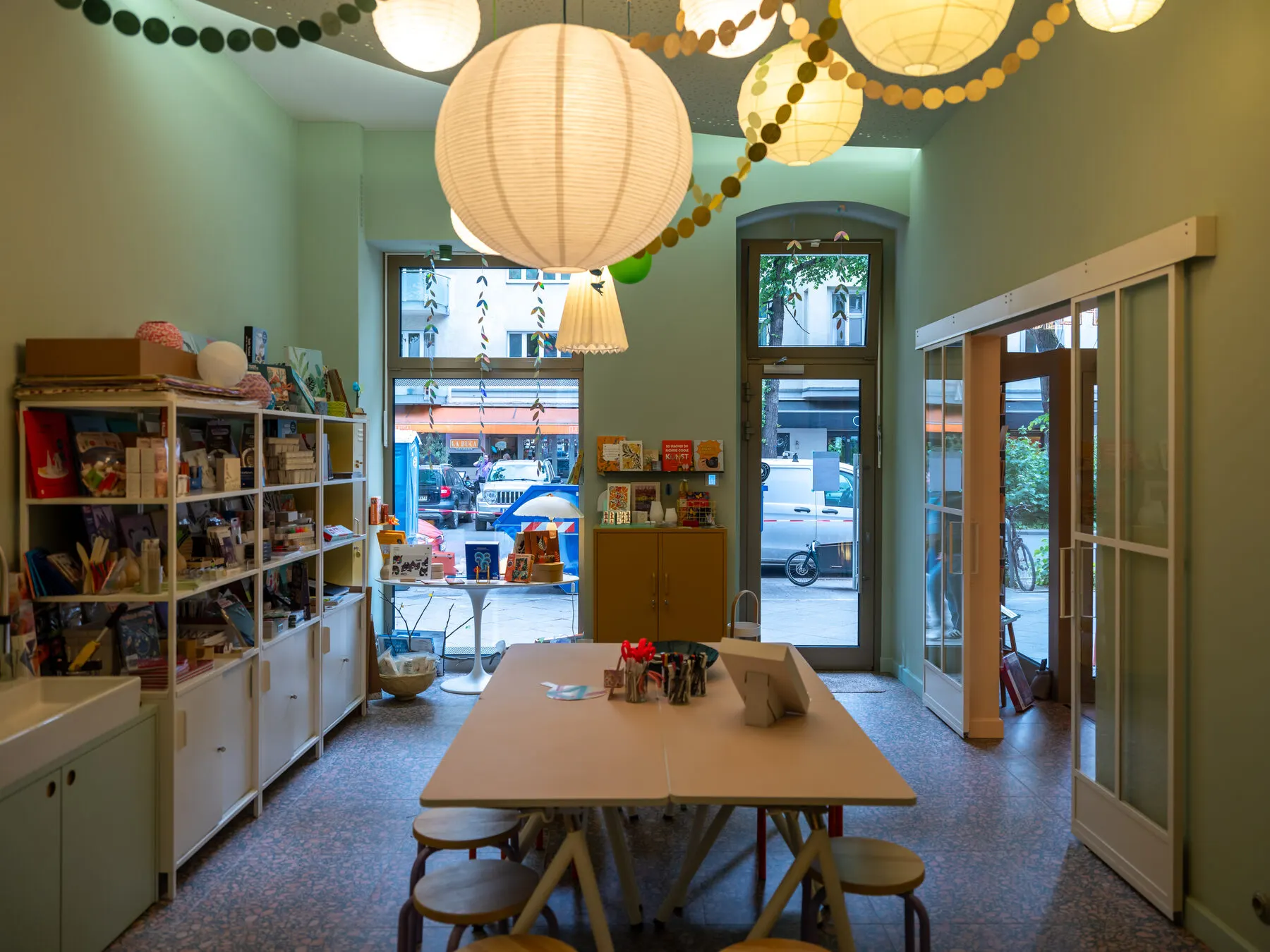 Der 50 m² große Workshopraum von L' Atelier Papier in Berlin-Charlottenburg mit Arbeitstischen, Regalen und Papierlampen