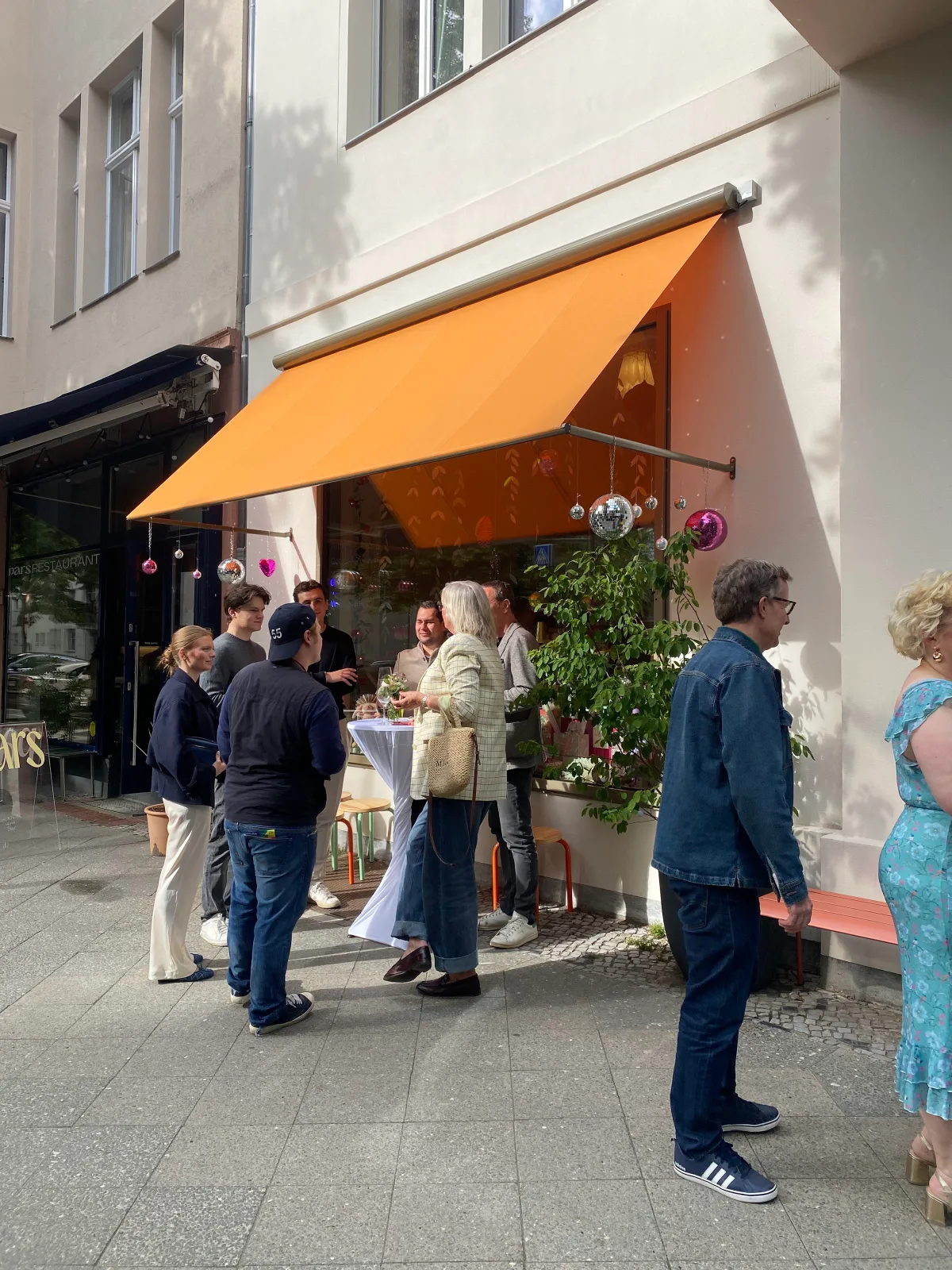 Gäste unter der orangefarbenen Markise vor L' Atelier Papier beim INESSA-Pop-up, Grolmanstraße 52, Berlin-Charlottenburg