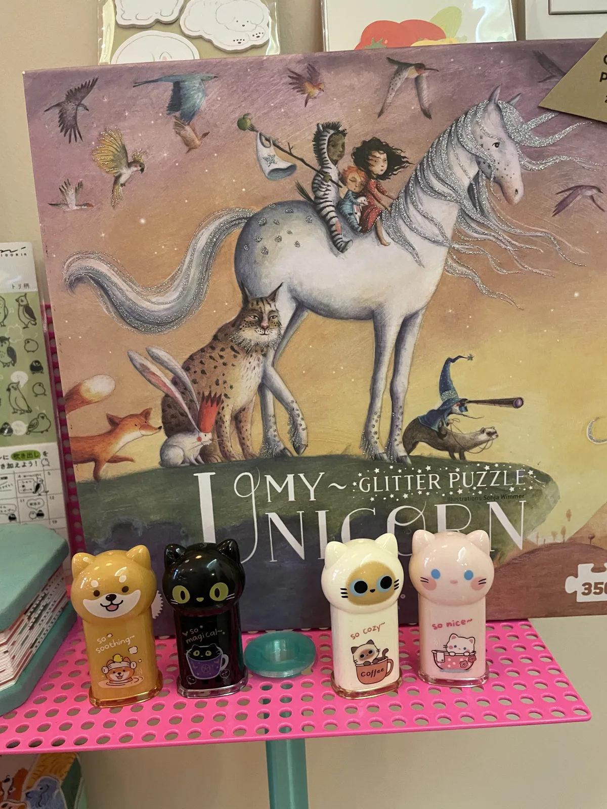 Glitzer-Puzzle mit Einhorn-Motiv und kleine Tierfiguren auf einem pinken Regalbrett