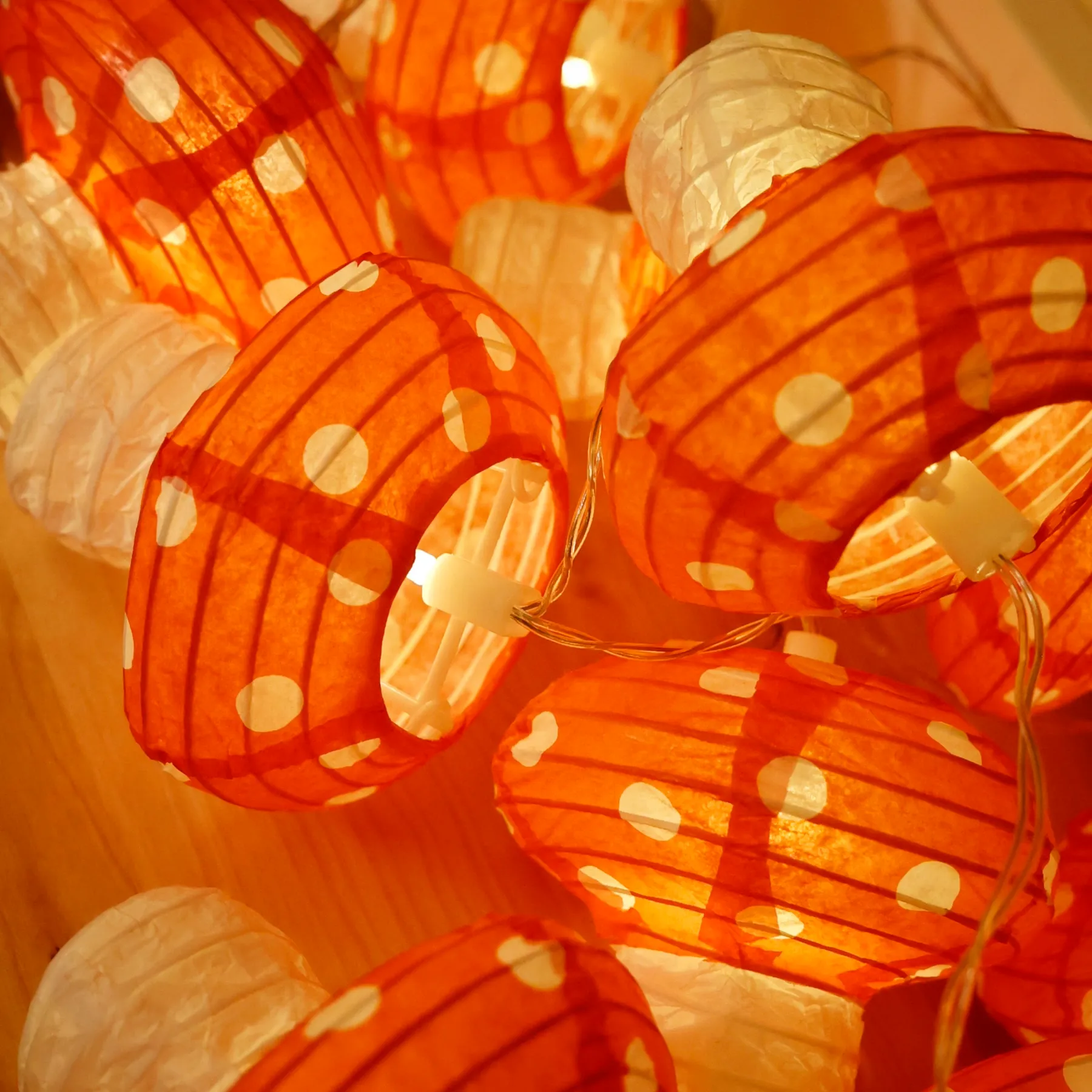 Orange Papierlampions mit weißen Punkten als Lichterkette