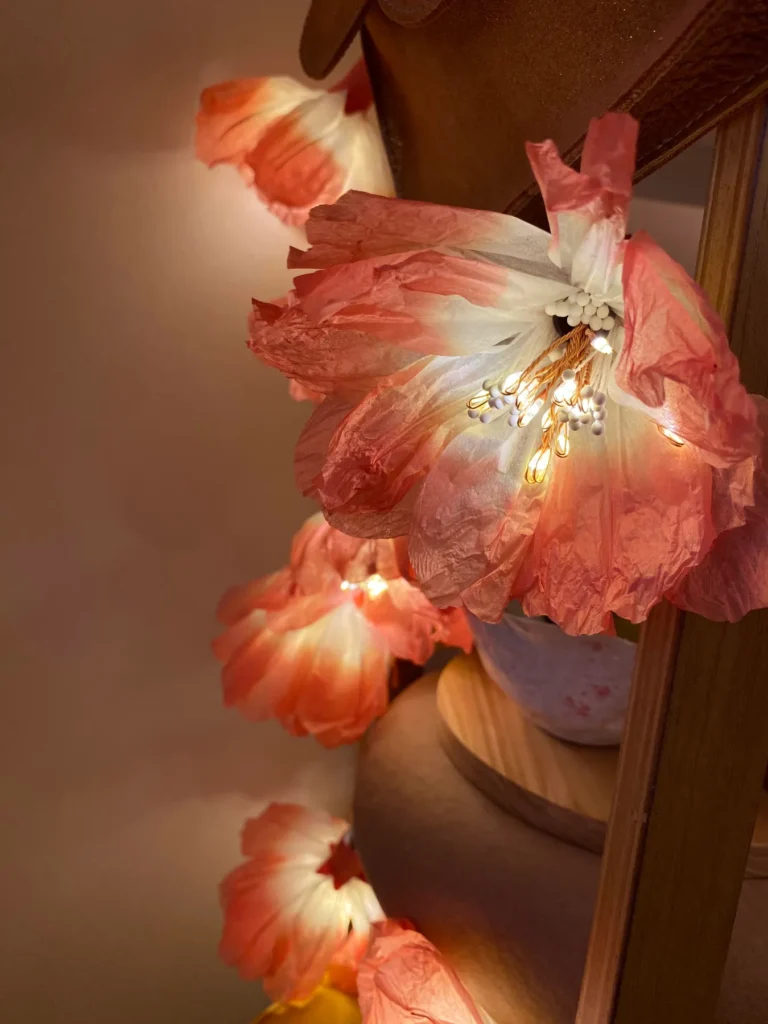 Girlande aus Papierblüten in Rosa und Orange mit Lichterkette