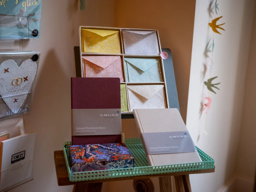 Bunte Briefumschläge und zwei Notizbücher auf einem grünen Tablett im L' Atelier Papier, Grolmanstraße 52, Berlin-Charlottenburg
