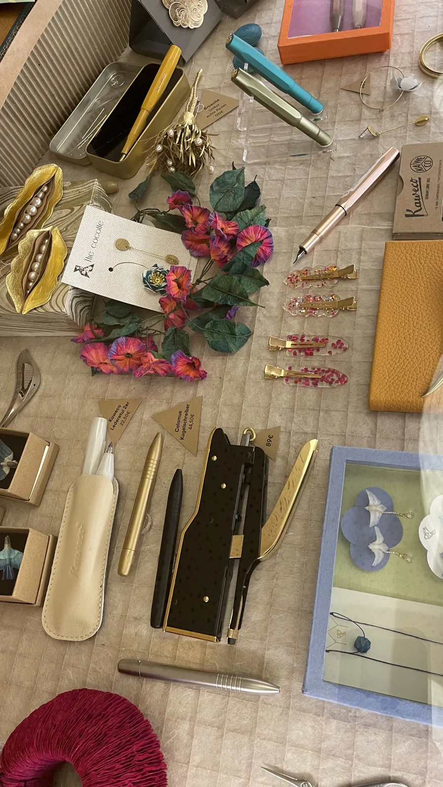 Vitrine an der Kasse von L' Atelier Papier: Schreibgeräte, Papierschmuck und Papierblüten in der Draufsicht