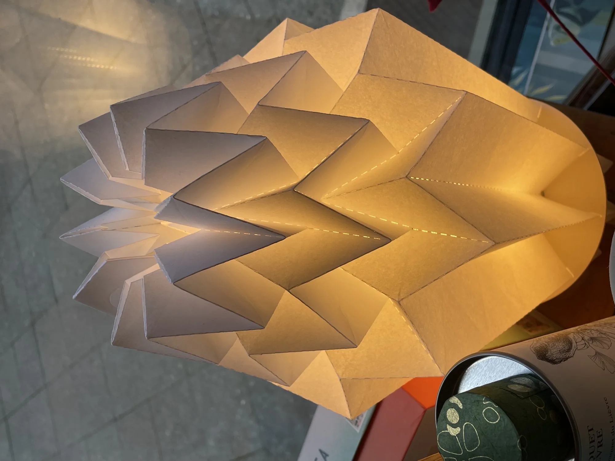Aufgefaltete Papierleuchte mit Origami-Falten, von innen warm beleuchtet