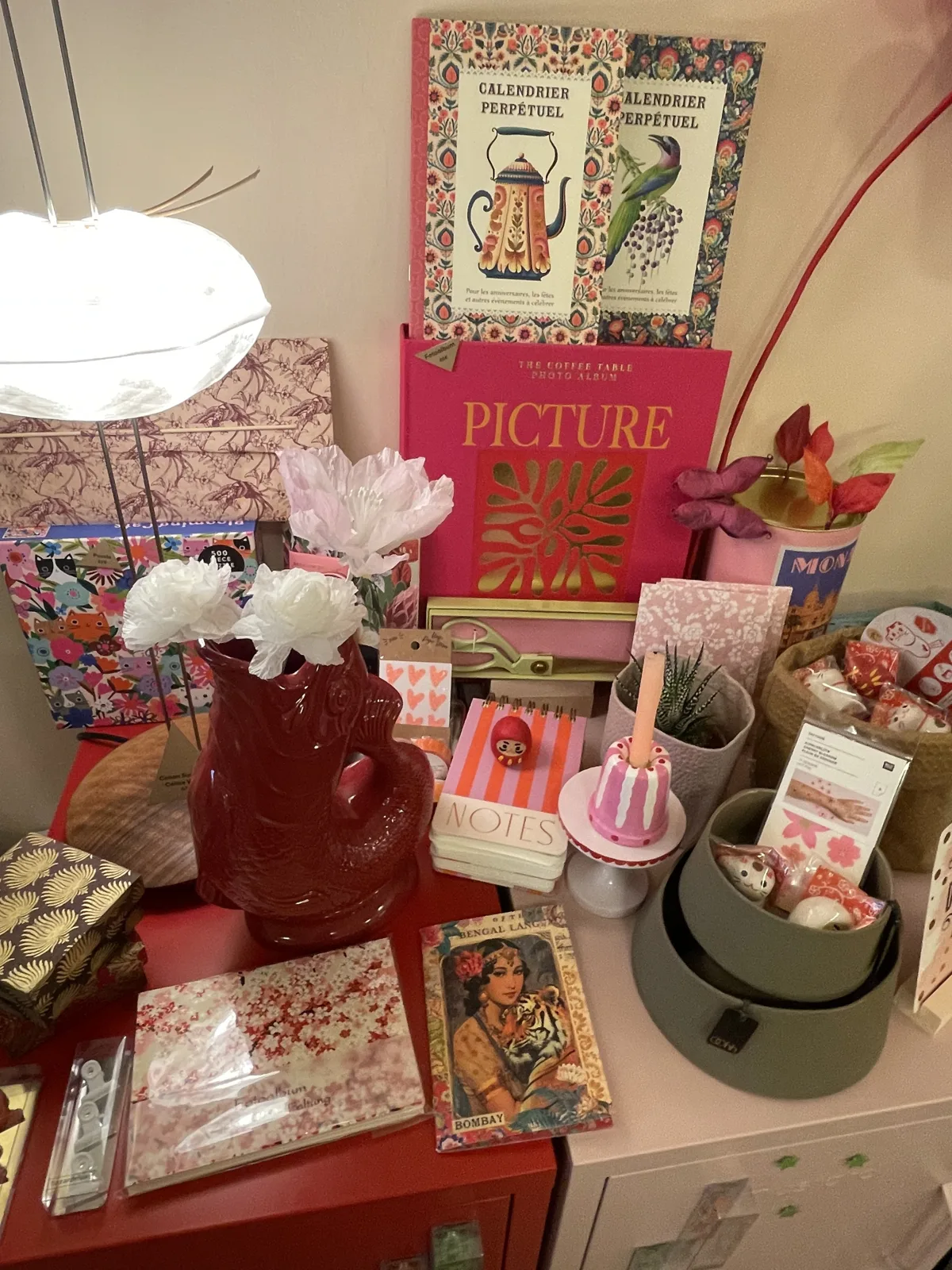 Tisch im Concept Store mit Bildbänden, einer Vase in Fischform, Notizbüchern und Papierblumen